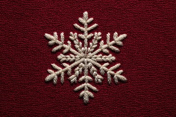 A snowflake embroidered on dark red fabric.