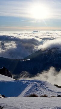 Misty winter sunrise timelapse with fog dancing over snow covered mountain slopes and forest vertical view