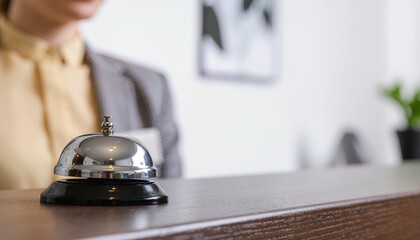 Service bell on counter with blurry staff in hotel reception area