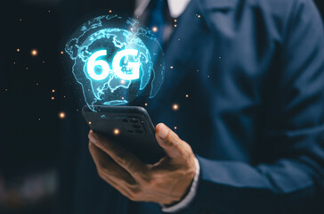 A person holds a smartphone showing a glowing 6G hologram around a digital globe, symbolizing future mobile networks, ultra-low latency communication, advanced wireless technology.