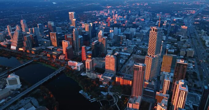 High-rises of Austin, Texas, USA lit by the setting sun. Drone flight high above the cityscape approaching the Colorado River.