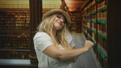Woman wearing straw hat and white blouse pointing finger and dancing amid bookshelves in a historic library building  joyful playful carefree. © Krakenimages.com