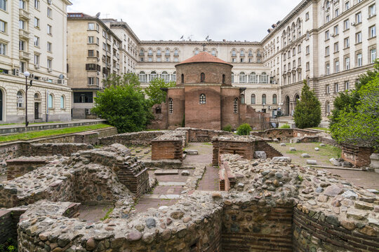 View of ancient ruins contrasting with modern architecture under a cloudy sky, creating a timeless blend of history and progress, Sofia, Sofia City Province, Bulgaria.