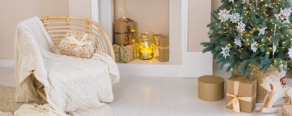 Cozy Christmas holiday interior with decorated tree, gift boxes and comfy chair. Winter celebration and seasonal home decor concept.