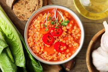 Delicious lentil soup with vegetables served on wooden table, flat lay