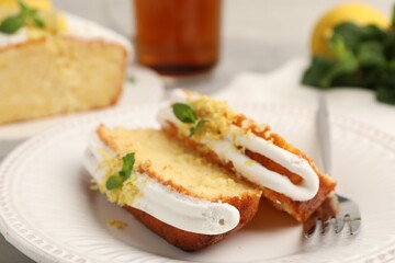 Delicious lemon cake with glaze, fresh fruit slices and mint served on table, closeup