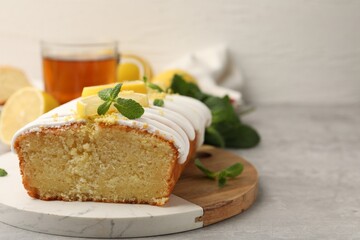 Delicious lemon cake with glaze, fresh fruit slices and mint on gray table, closeup. Space for text