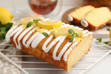 Delicious lemon cake with glaze, fresh fruit slices and mint on light table, closeup