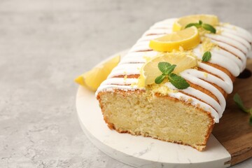 Delicious lemon cake with glaze, fresh fruit slices and mint on gray textured table, closeup. Space for text