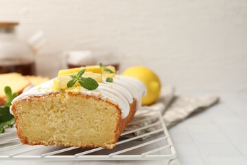 Delicious lemon cake with glaze, fresh fruit slices and mint on light table, closeup. Space for text