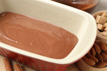 Liquid chocolate dough, brown sugar, cinnamon and nuts on table, closeup