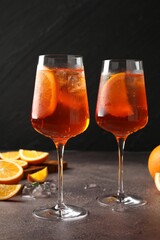 Glasses of refreshing spritzer cocktail and oranges on grey table