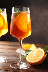 Glasses of refreshing spritzer cocktail and oranges on wooden table