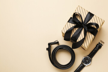 Beautiful wrapped gift box and men's accessories on beige background, flat lay. Space for text
