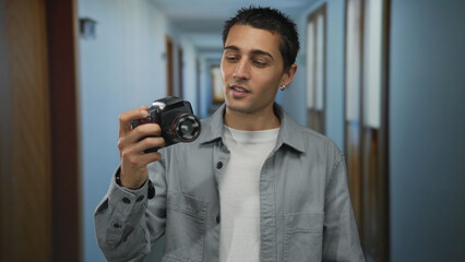 Young man photographing himself with camera in hotel hallway, capturing indoor hotel environment highlighting personal moments and creativity in a casual setting.