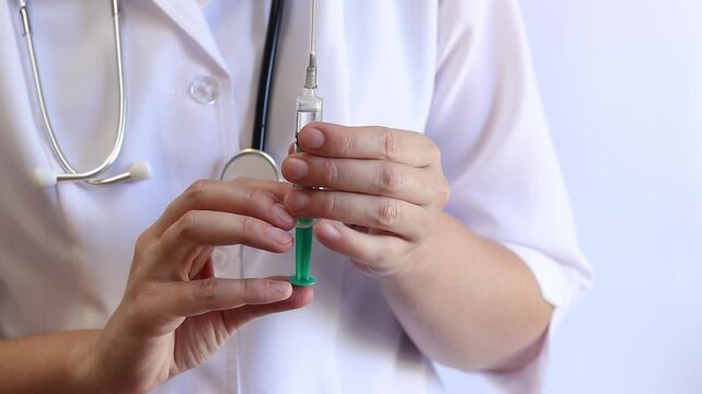 Doctor or nurse with a syringe in her hands. Hands close-up holding a syringe with medicine. Nurse releases air bubbles from the liquid in the syringe. Medicine