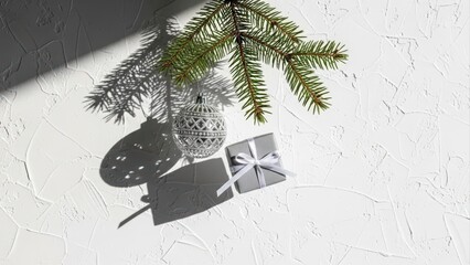 Christmas tree branch with silver ornament and gift box on white background.