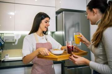 Woman Serving Fresh Juices and Cookies to Friend