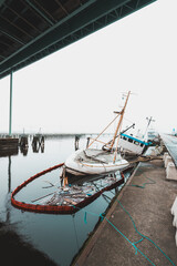 Naklejka premium Sunken ship near bridge in Gothenburg with water reflecting the cloudy sky