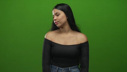 Naklejka premium Woman turning head with bare shoulders in front of green screen in studio under soft lighting; contemplation reflection.