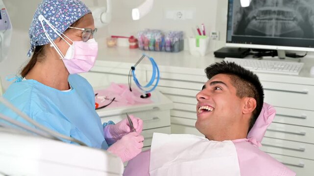 Friendly dentist talking with a smiling patient during a dental consultation, explaining the procedure in a modern clinic, captured in clean 4K video. High quality 4k footage
