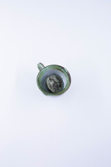 A decayed lemon with mold inside a ceramic cup, photographed from above to highlight spoilage and contamination.