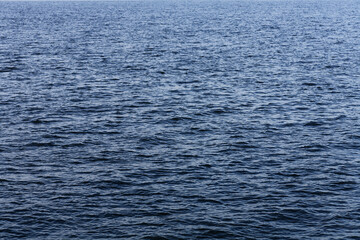 Serene Ocean Waves: Sunlit Water Ripples on Calm Blue Sea, Horizontal Close-Up Shot