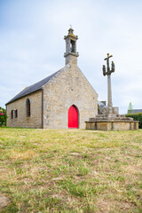 Chapelle Pol, a small granite church in Brignogan-Plages, and the nearby calvary cross and sentry box carved in the rock. Finistere, Brittany, France. Vertical shot.