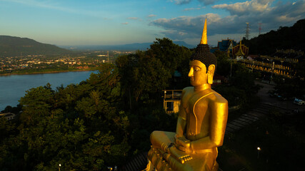 Aerial view at sunset above the Mekong river in Laos revealing Pakse city golden giant buddha