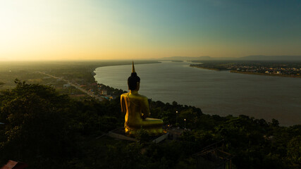Aerial view at sunset above the Mekong river in Laos revealing Pakse city golden giant buddha