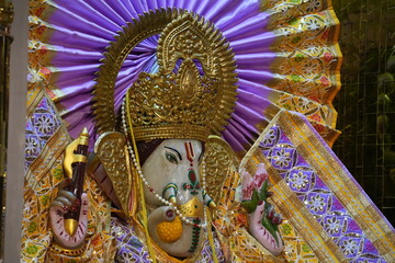 Lord Ganesha Idol in Hindu Temple with Floral Decorations and Spiritual Background
