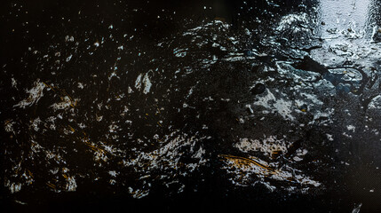 Closeup of greasy stovetop surface; grease streaks spread across dark metal as grease mixes with soap residue and burnt splatter, highlighting cleaning challenge and kitchen realism in cleanup theme