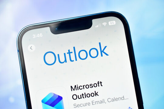 Close up of microsoft outlook app icon and name displayed on a modern smartphone screen with a soft blue background