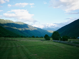 Naklejka premium Landscape valley mountains countryside with expansive fields and greenery under a sky with scattered clouds, creating a tranquil meadow scene in open rural scenery