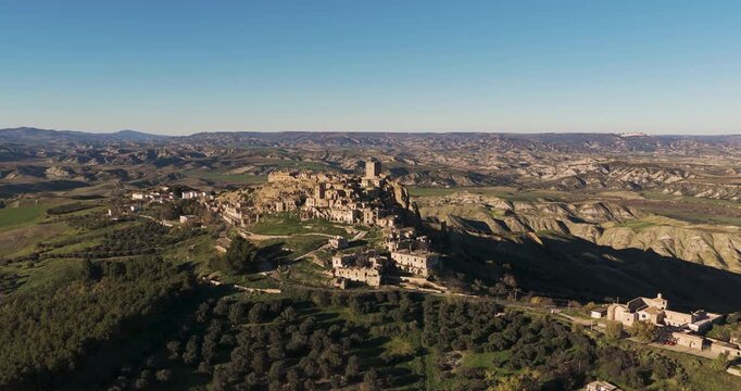 Aerial view of the abandoned medieval village of Craco, with its stone buildings and tower perched atop a hill, Basilicata, Italy.