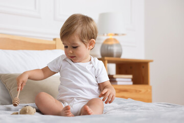 Fototapeta premium Cute little boy playing with toys on bed at home, space for text
