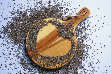 Chia seeds on wooden board on white table. Flat lay, copy space