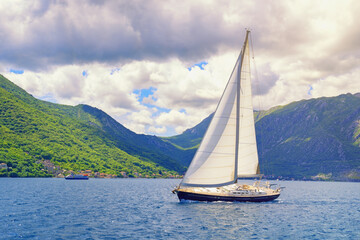 Beautiful Mediterranean landscape. Sailboat with white sail on water. Cloudscape. Vacations, recreation, sport concepts. Montenegro, Adriatic Sea, Bay of Kotor
