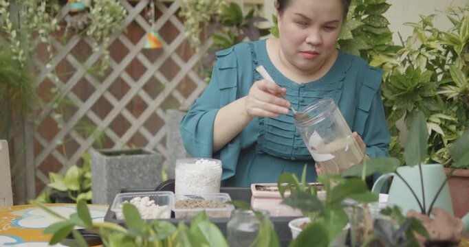 A blind gardener, person with blindness disability scooping different growing media in containers into pot to grow plants in home garden nature background