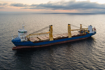 Fototapeta premium Aerial view of a large blue cargo ship anchored in the open waters of the Baltic Sea near the coast of Estonia at sunset or sunrise.