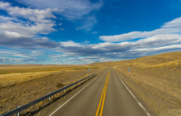 Asphalt road leading to the distant horizon across flat terrain, featuring travel infrastructure, scenic transport route, mobility concept, open landscape perspective ideal for journey themes pathways