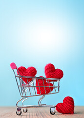 The red Heart shapes in shopping cart on blue background , love concept for shopping on valentines day
