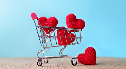 The red Heart shapes in shopping cart on blue background , love concept for shopping on valentines day