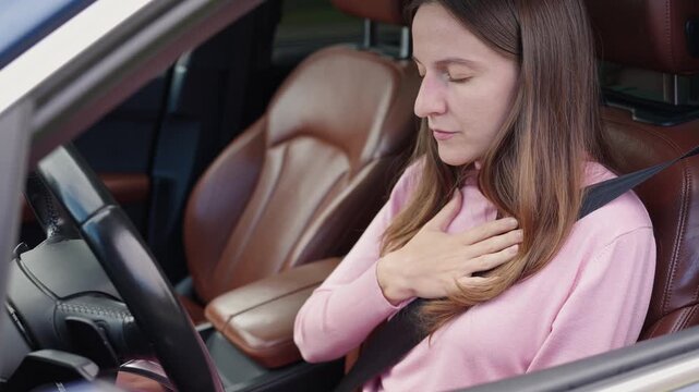 Woman in car practices deep breathing exercises with hand on chest, trying to recover from panic attack, anxiety, heart attack, and heart palpitations.