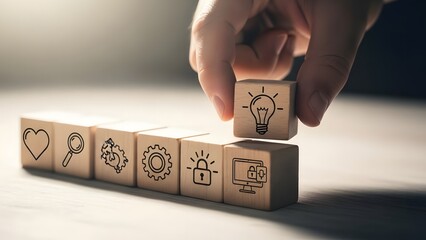 Hand choosing a block with a lightbulb icon from a row of wooden blocks