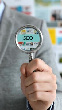 Human hand holding a magnifier displaying SEO concept. Digital marketing strategy planning, online visibility analysis and web content ranking for enterprise success.