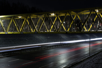 Yellow bridge with moving car light trails on a night road