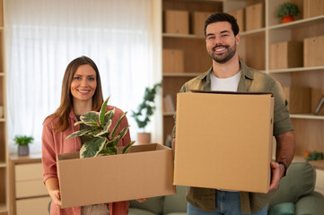 Happy couple holding boxes moving into new home