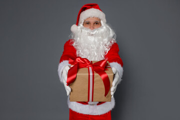Santa Claus with Christmas gift on grey background