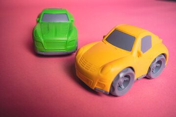 Two toy cars on a pink background during a play session with friends in a simple setting